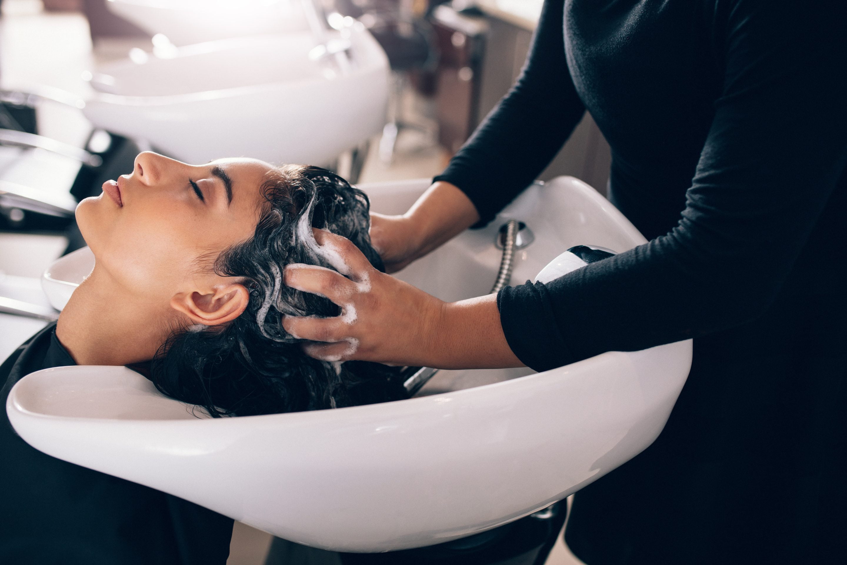 Coiffeuse effectuant un massage de tête pendant un soin capillaire en 2023